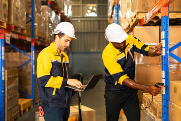 Two workers in a warehouse, one using a laptop and the other scanning items on shelves, showcasing teamwork and efficiency.