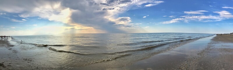 Panorama of tranquil ocean waves under a dynamic and bright sky