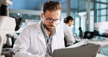 Reading, laptop and research with man in laboratory for clinical trail, online and science. Medical...