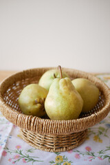 Pears arranged in a wicker basket on a floral tablecloth