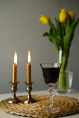 vertical photo Shabbat scene with two lit Sabbath candles in silver candlesticks, a glass of red wine. Shabbat Shalom