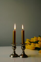 Shabbat Candles with yellow tulips. Jewish Tradition and Peaceful Home Atmosphere. Shabbat Shalom