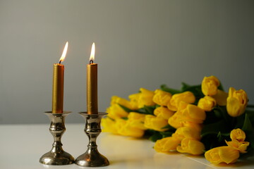Shabbat Candles with yellow tulips. Jewish Tradition and Peaceful Home Atmosphere. Shabbat Shalom