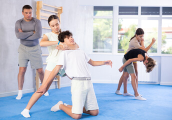 Boy and girl training self-defense techniques in group in studio