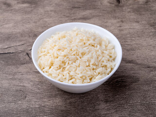 Cooked white rice in a bowl over wooden table