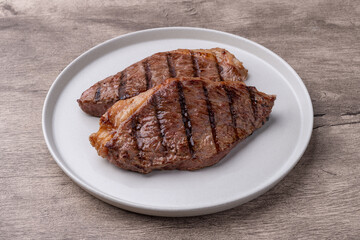 Grilled picanha beefs in a plate over wooden table