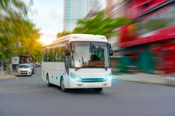 Fototapeta premium Tourist bus driving moving turn on the left at high motion blur effect speed on a street in the sunset