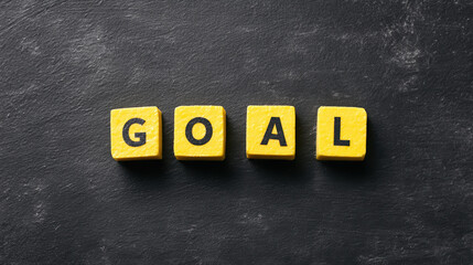 Yellow blocks spelling "GOAL" on a dark surface, symbolizing aspirations and achievements in a visually striking and motivational manner.
