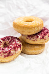 Stack of donuts with berry crumble topping and sugar glaze on a white textured background — sweet, tasty, and inviting dessert concept.Tower of assorted donuts with sugar coat