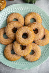 Pumpkin spice oven baked doughnuts, pumpkin puree baked goods, pumpkins,  kitchen towel, grey background. sugar coated donuts with pumpkin
