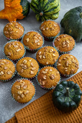 Pumpkin spice cupcakes, pumpkin puree baked goods, pumpkins,  kitchen towel, grey background. muffins with pumpkin and nuts