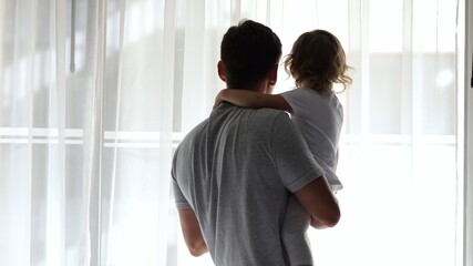 Father and daughter sharing a tender moment at hotel window