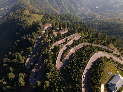 Aerial view of winding road through lush forest and majestic mountains, Pir Chinasi, Azad Jammu Kashmir, Pakistan.