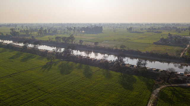 Aerial view of BRB Canal surrounded by vibrant green fields and tranquil rural landscape, Lahore, Punjab, Pakistan.