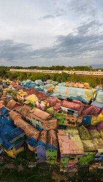 Aerial view of vibrant colorful houses and rooftops with a train passing through, Blimbing, East Java, Indonesia.