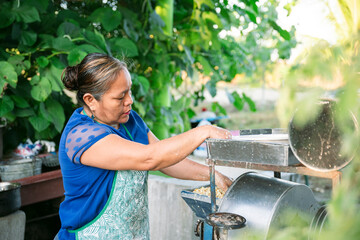 Latin american woman grinding corn in traditional metal grinder outdoors