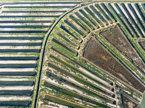 Aerial view of vibrant salt works and agricultural fields with intricate patterns, Isla Cristina, Huelva, Spain.