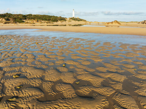 Aerial view of tranquil Trafalgar beach with a lighthouse and scenic coastline, Barbate, Cadiz, Spain.