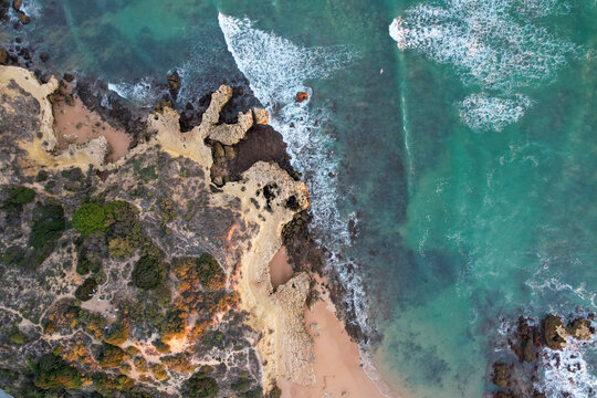 Aerial view of beautiful cliff beach with rugged rocks and turquoise water, Algave, Portugal.