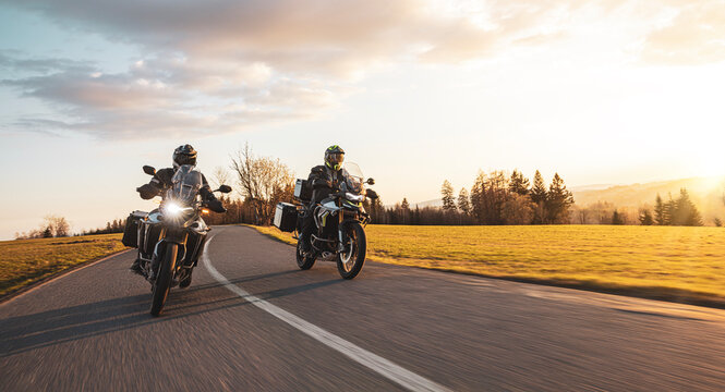 Two Drivers Riding Motorcycle on Empty Road During Sunset. Travel in Nature. Beautiful Evening Light with Blur Motion Effect on Road. Front View.