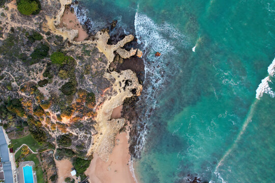Aerial view of beautiful cliff beach with rocks and turquoise ocean waves, Algave, Portugal.