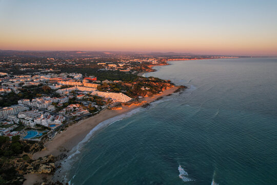 Aerial view of beautiful beach at sunset with ocean waves and serene shoreline, Algave, Portugal.