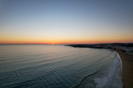 Aerial view of beautiful sandy beach at sunset with calm ocean waves, Algave, Portugal.