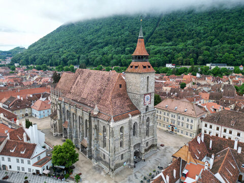 Aerial view of the historic biserica church surrounded by picturesque rooftops and scenic mountains, Brasov, Brasov, Romania.