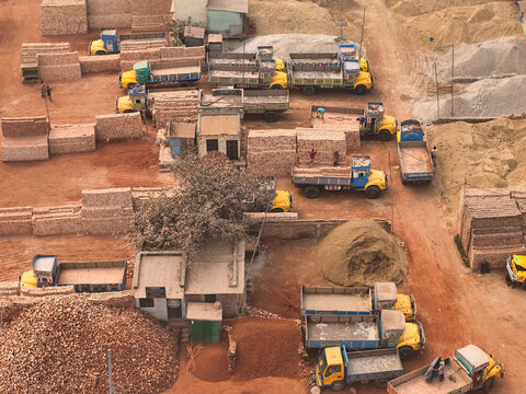 Aerial view of a brick factory with yellow trucks and heavy equipment in an industrial area, Darus Salam Thana, Dhaka, Bangladesh.