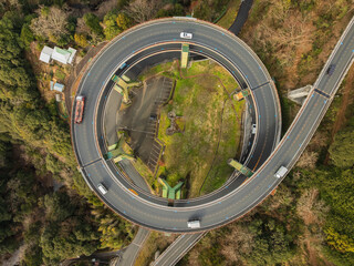 Aerial view of circular freeway ramp surrounded by lush greenery and forest, Kawazu Cho, Kamo District, Shizuoka, Japan.