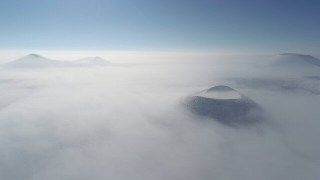 Aerial view of majestic mountain peaks shrouded in fog and clouds at sunrise, Karapinar, Konya, Turkiye.