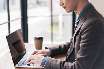 ノートパソコンを開き仕事をしている日本人男性。