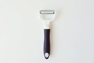 White plastic vegetable peeler with metal blade and dark blue handle. White background.