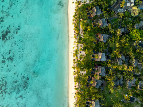 Aerial view of tropical beach with luxurious villas and palm trees along the turquoise coastline, Trou aux Biches, Pamplemousses, Mauritius.
