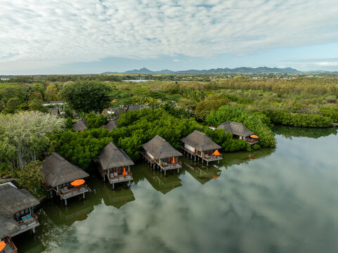 Aerial view of luxurious bungalows and serene water surrounded by tropical greenery and mountains, Prince Maurice, Flacq, Mauritius.