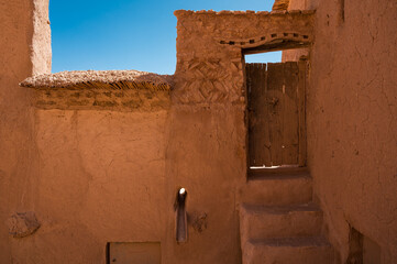 old wooden door and braun walls, detail of fortification Ajt Bin Haddu in Morocco.