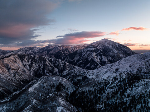 Aerial view of majestic snow-covered mountains at sunset with serene woodland and crisp sky, Sundance, Utah, United States.
