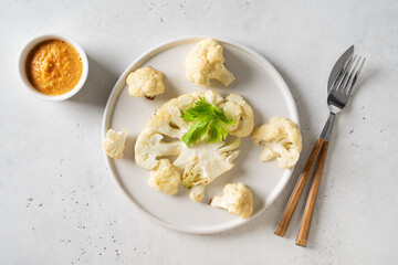 Grilled cauliflower with sauce on plate on white background