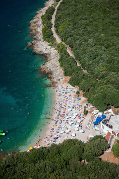 Aerial view of ambrela beach with turquoise sea and crowded umbrellas, Pula, Istria, Croatia.