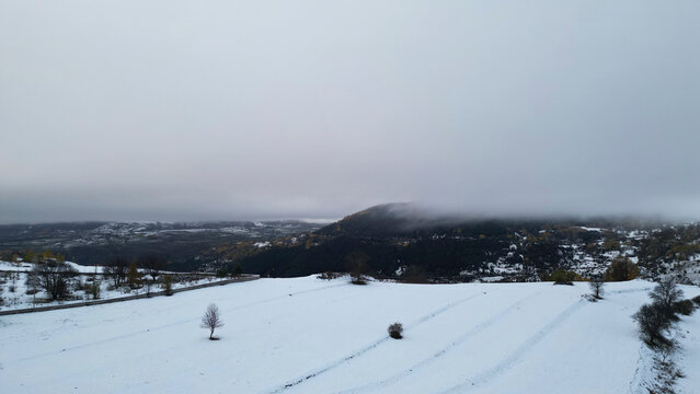 Aerial view of snow-covered mountains and tranquil forests under a cloudy sky, Posof, Ardahan, Turkiye.
