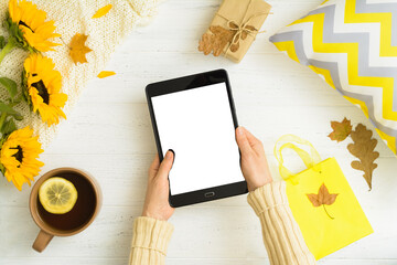 Cozy home concept. Autumn flat lay with female hands holding tablet with copy space. Mockup
