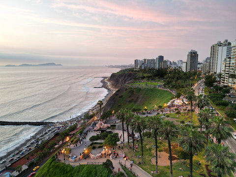 Aerial view of parques del amor with beautiful palm trees and ocean at sunset, Miraflores, Lima Province, Peru.