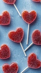 Obraz premium Heart shaped candies on white sticks arranged on textured blue background