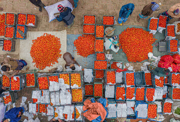 Shibganj, Bangladesh - 28 January 2021: Aerial view of busy wholesale tomato market with colorful crates and fresh produce, Roynagar, Shibganj, Rajshahi, Bangladesh.