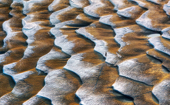Aerial view of people crossing a beautiful sandbar with wavy patterns, Sariakandi, Rajshahi, Bangladesh.