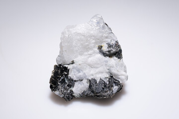 Raw moonstone crystal specimen with dark inclusions against a plain white background, showcasing...