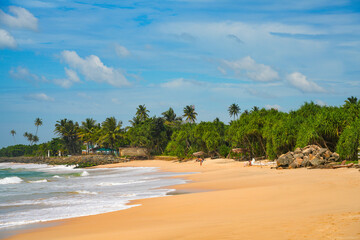 Koggala beach with blue cloudy sky and foamy waves, Koggala, Sri Lanka, 