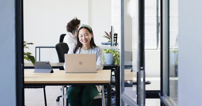 colleagues talking on phone cheering smiling, using laptop computer in modern office
