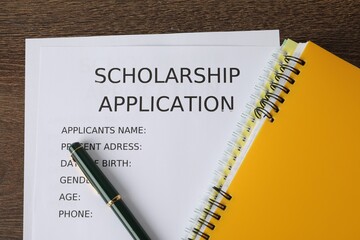 Scholarship application form, pen and notebooks on wooden table, flat lay