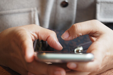 Person using smartphone while sitting at wooden table